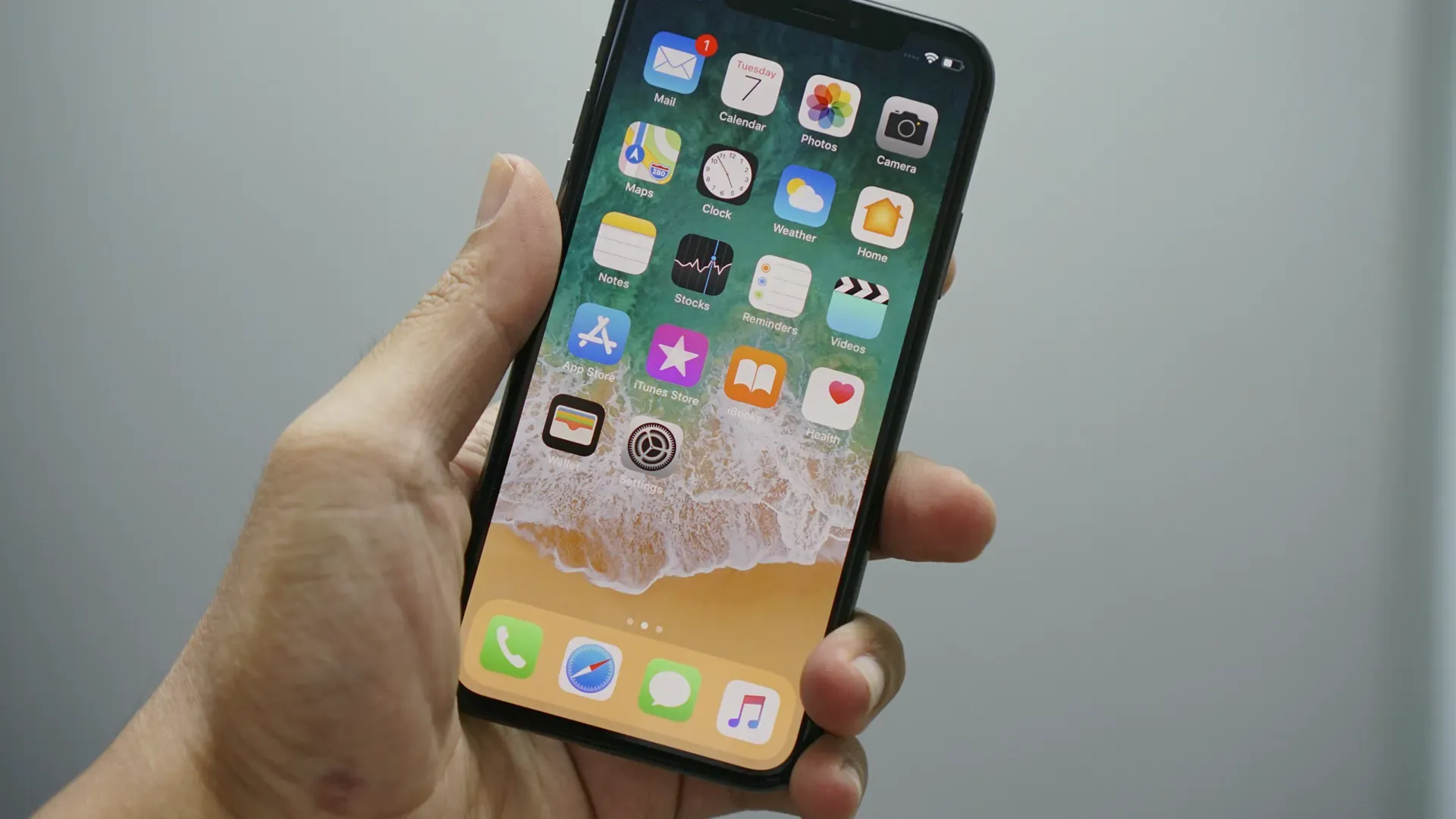 A hand holding a smartphone showing a home screen of app icons